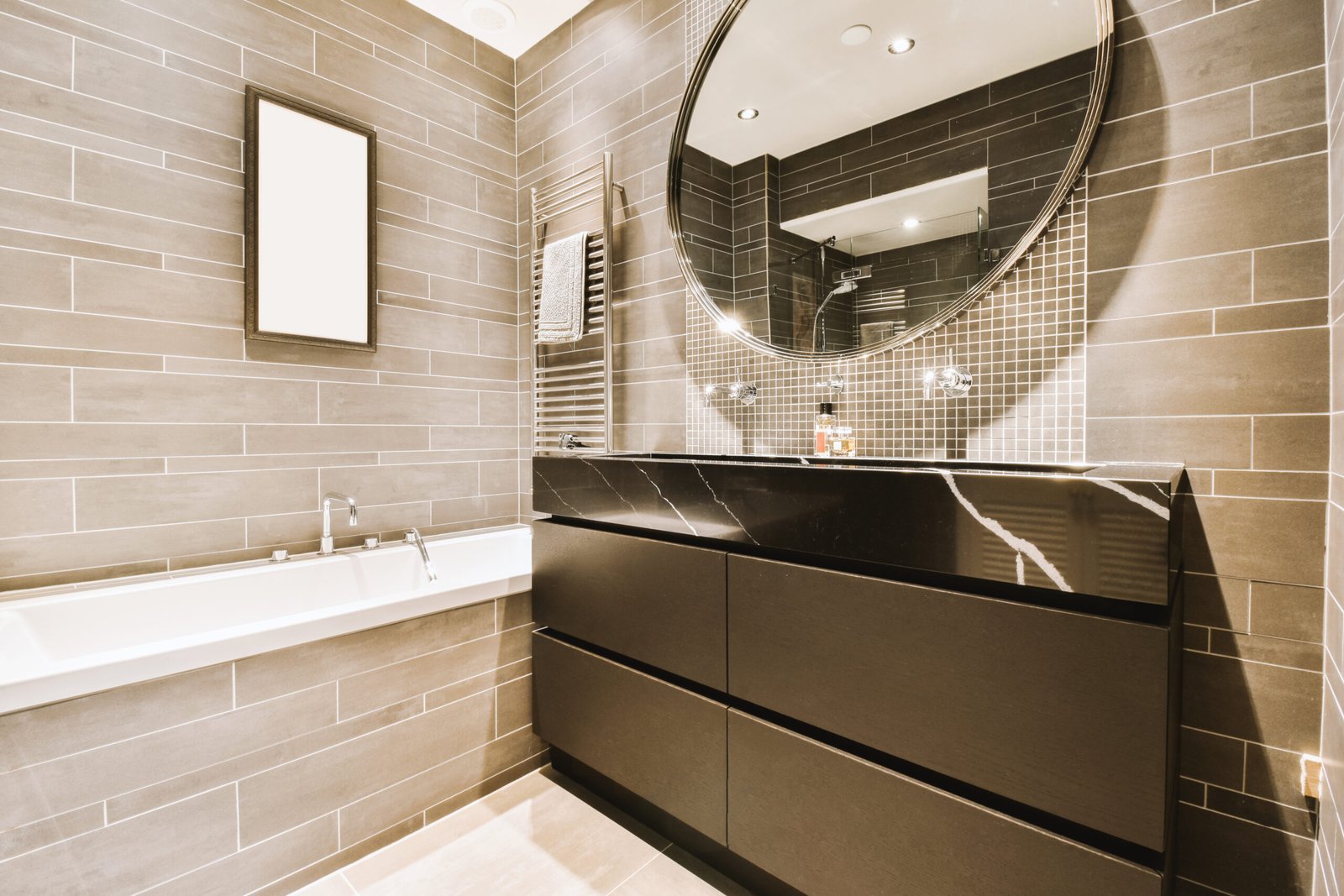 a modern bathroom with gray tile walls and white tiles on the floor, along with a large mirror over the bathtub