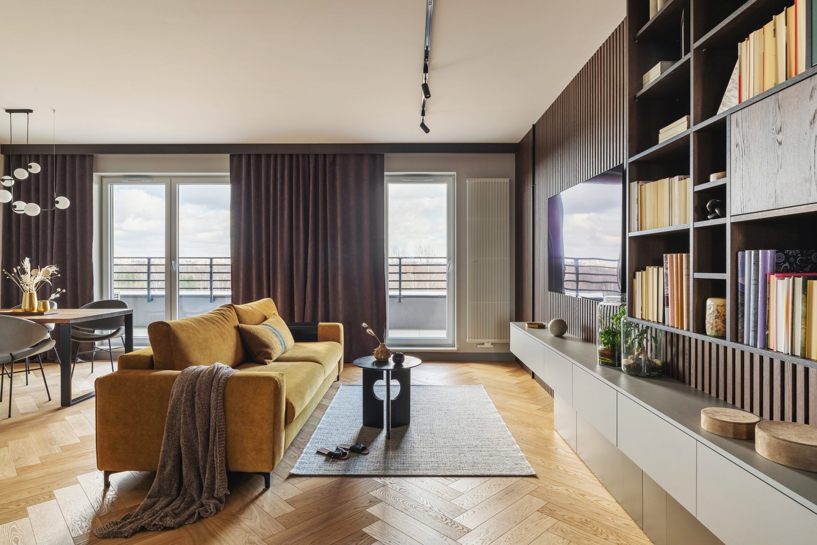 Creative and modern vintage living room interior design with yellow sofa and coffe table on grey carpet. Lamella wall with tv, bookcase and chest of drawers . Herringbone parquet., Brown curtain in windows. Template.